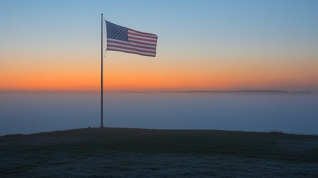 Sunrise over foggy coast, American flag on hilltop, patriotic scene