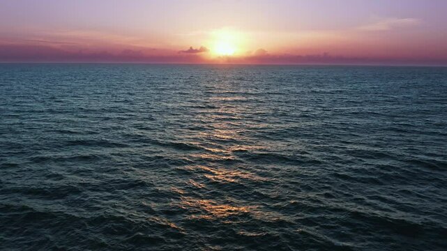 Top view to the ocean in summer day while sunset - closeup.  Aerial view over beautiful  ocean during  sunset. Drone view of a Scenic slow motion ocean waves. Beautiful sunrise over ocean