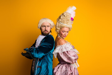 Elegant Couple in Period Costumes Posing Against Vibrant Yellow Background