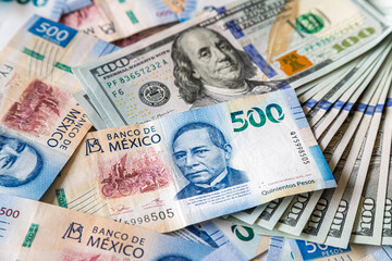 Macro close-up of 500 Mexican Pesos and 100 Dollar bills mixed up