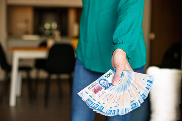 Woman shows a fan of 500 Mexican peso banknotes in her home