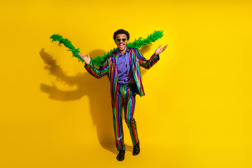 Young man in a vibrant suit posing against a bright yellow background expressing positivity and...