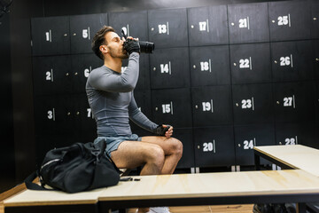 Man drinks pre workout drink in the dressing room.