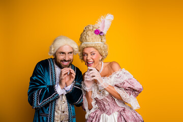 Elegant Couple in Royal Vintage Costumes Laughing Against a Bold Yellow Background