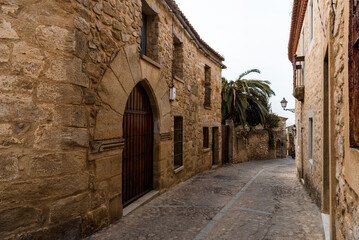 Obraz premium Explore a winding cobblestone street surrounded by historic stone buildings in Trujillo, Spain.