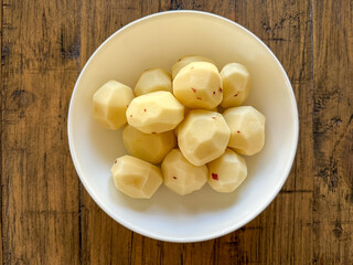 Peeled, Round, Red-Skinned Potatoes In A White Bowl On A Wooden Table