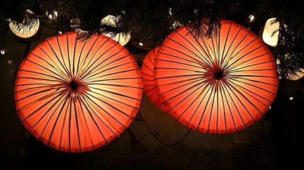 Illuminated orange paper umbrellas hanging at night, creating a warm and inviting atmosphere.  Perfect for Asian-themed designs or festive backgrounds.