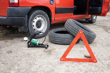 Car breakdown. Wheel replacement, tire. Pump up the car wheel with a pump. Red emergency stop sign