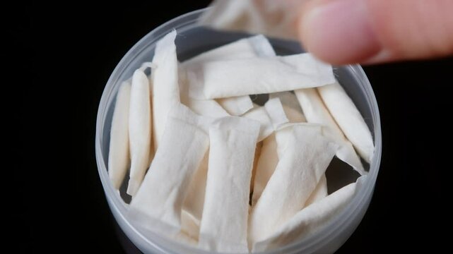 Snus nicotine tobacco close up, pack of tobacco for gum. unhealthy addiction. Man opening box with snus and taking one. 