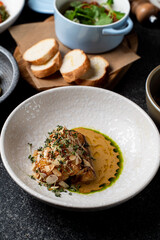 Exquisite culinary presentation featuring a beautifully plated dish, highlighting rich textures and fresh herbs, set against a cozy dining atmosphere with artisanal bread