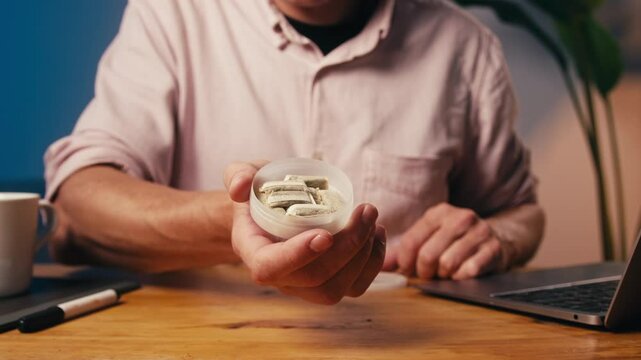 Snus nicotine tobacco close up, pack of tobacco for gum. unhealthy addiction. Man opening box with snus and taking one. 