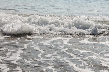 Ocean waves with white foamy water. Close-up of sea wave breaking. Water surface with waves and foam. Detail of ocean wave cresting. White water foam on sea surface