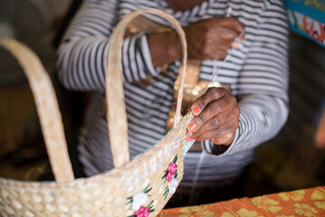 Artisan weaving a handmade straw basket at a local market in the Bahamas