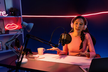 Smiling creative young beautiful Asian influencer talking in channel with positive podcast speech...