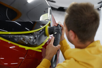 Service technician polishing headlamps at car garage workshop