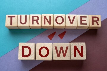 A visual representation of the phrase "Turnover Down" using wooden blocks on a colorful background.