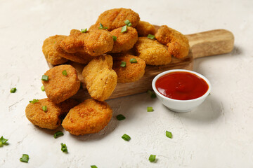 Wooden board with tasty nuggets and ketchup on light background