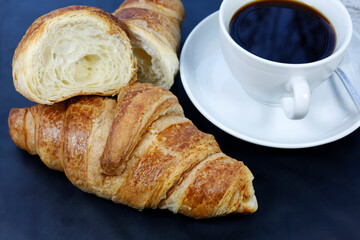 cup of coffee and croissant on a wooden board