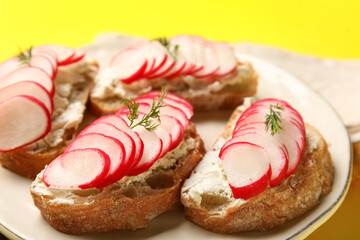Plate with delicious radish bruschettas on yellow background