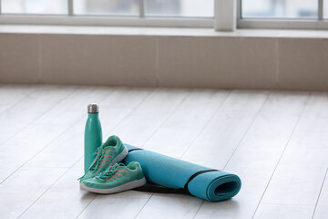 Yoga mat with sneakers and bottle of water in gym