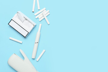 Modern electronic cigar, pack and sticks on blue background