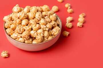 Bowl with crispy popcorn on red background