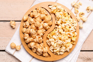 Plate with crispy popcorn on white wooden background