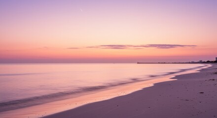 Serene beach at sunset with gentle waves and distant city skyline