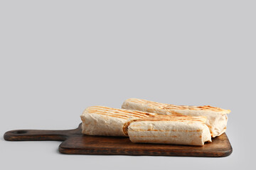 Board with tasty shawarma on grey background