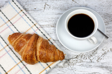 kruvasan cup of coffee and croissant on a rustic white wooden	