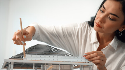 Professional young beautiful architect engineer using ruler and pencil measuring model roof length...