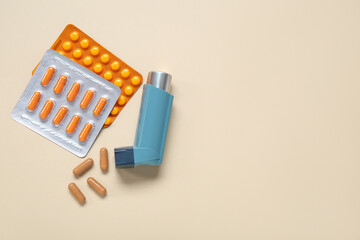 Asthma inhaler and pills on beige background
