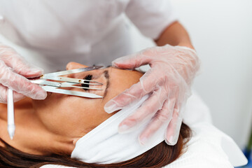 Beautiful young adult woman receiving professional permanent makeup treatment. Modern face and...