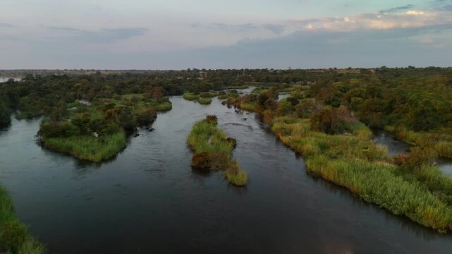 Aerial drone view of the Okavango River at sunrise on the Namibia-Angola border, Africa. The river features a shore and green vegetation.