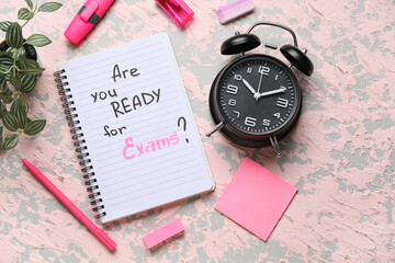 Notebook with question ARE YOU READY FOR EXAM?, alarm clock and different stationery on grunge pink...
