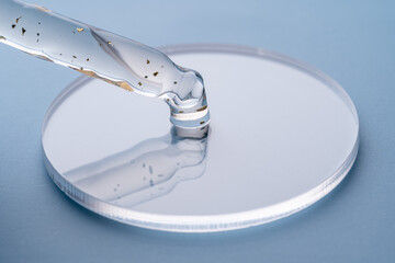 Close-up of cosmetic pipette dripping liquid on petri dish