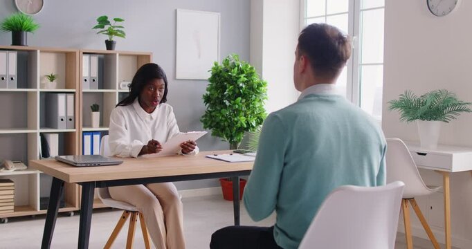 Confident african american woman hr manager sitting at the desk on meeting interviewing male candidate for vacancy company sitting in office. Job seekers and employee recruit concept. 4k video.