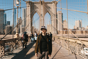 Young man exploring Brooklyn Bridge in sunny urban scene in New York