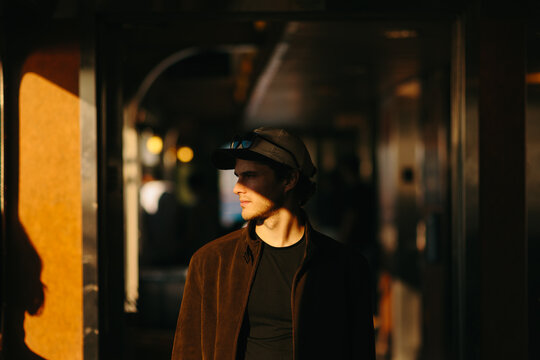 Man in moody sunlight wearing cap and sunglasses indoors in New York