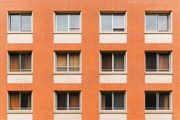 Building exterior featuring a brick facade with multiple windows showing various indoor curtains, captured in an urban setting during daytime