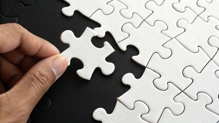 Fototapeta premium Completing the Puzzle: A close-up shot of a hand placing the last piece into a nearly completed jigsaw puzzle, illustrating the concepts of problem-solving and teamwork.