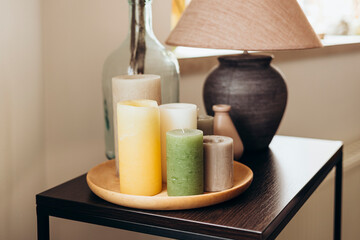 A set of colored candles on a table in a living room interior.