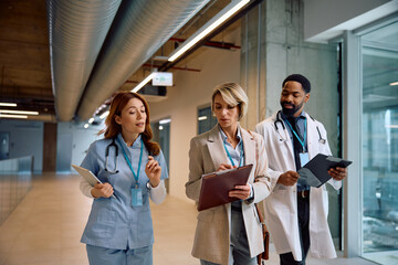 Businesswoman and doctors cooperating while analyzing document in hospital.