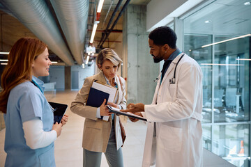 Hospital administrator analyzing reports with doctors at clinic.