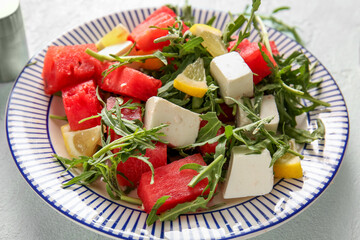 Plate of tasty watermelon salad on light blue background