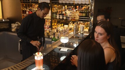 Couple talking at sitting bar with Margarita cocktail savoring sour tasty drink in happiness moment meeting while woman waiting friends at front view at luxurious counter vibrant nightclub. Vinosity.