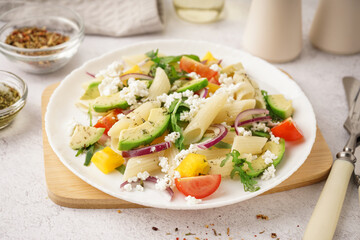 Plate of tasty pasta salad with tomatoes and avocado on white background