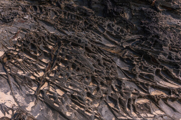 A rock with many holes and grooves, strange shapes in volcanic rock.