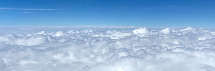 Obraz premium Fluffy clouds in bright blue sky, peaceful nature scene, perfect for travel or relaxation themes