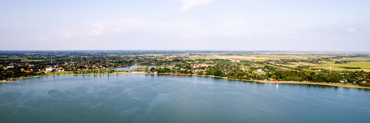 Expansive aerial view of serene lake and lush countryside, ideal for summer getaways and nature retreats